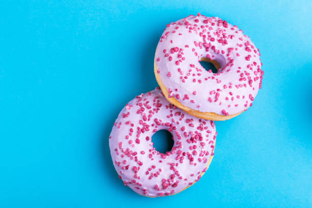 istock Two delicious lilac donuts with sprinkle on bright blue background 1097126342