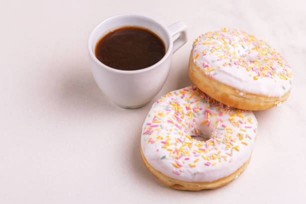 istock Two delicious vanilla donuts with sprinkle and cup of coffee on light marble background 1097126560