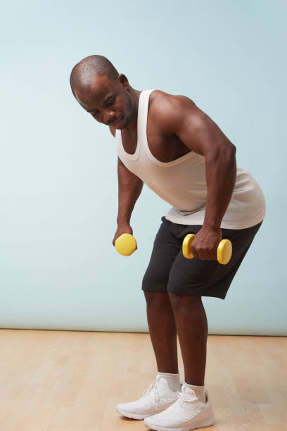 istock Handsome black man doing bent-over dumbbell rows. pale blue background 1097156266