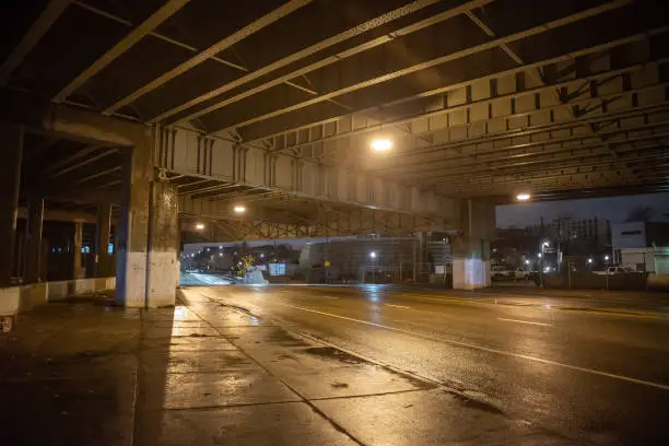 Photo of Gritty dark city highway bridge and street underpass at night in Chicago