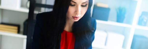istock Beautiful young girl is looking through documents, sitting in the office at the table. 1097159034