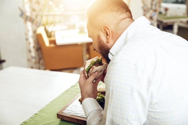 istock Back view man bite sandwich eating in cafe 1097160004