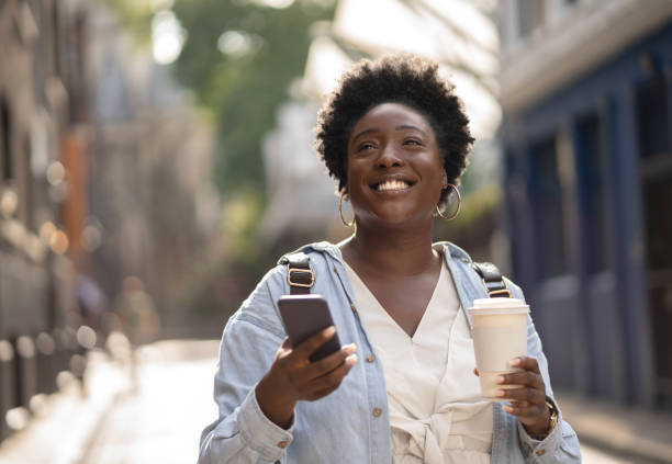 istock Happy woman using cell phone and drinking coffee outdoors 1097162322