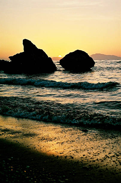 Captivating sunset at Zapallo Bay Beach in Cyprus, twilight setting in, sun dipping behind the mountain, creating a stunning evening scene