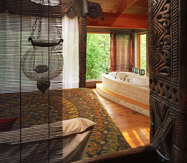 Master bed with woodcarvings on the post and the view of the jakuzzi bathtub by the window