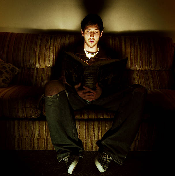 istock Young Man Sitting on Couch and Reading Heavy, Large Book 109718218