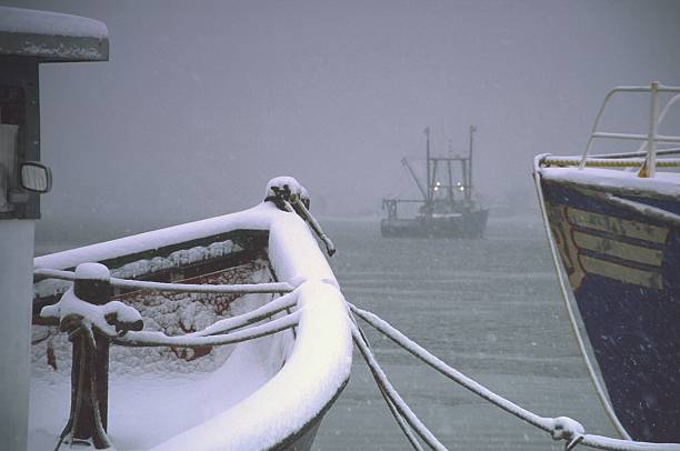 Winter landscape, lake shoreline and snow-covered boats.