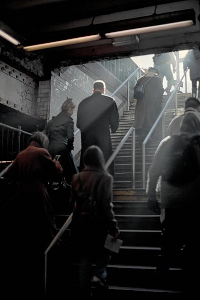 A man in a business suit is captured descending the steps of a subway entrance in an urban environment. The image captures the essence of daily commute and city life.