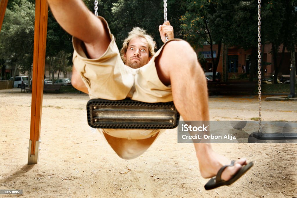 Uomo giocando su un Altalena al parco giochi Set - Foto stock royalty-free di Abbigliamento