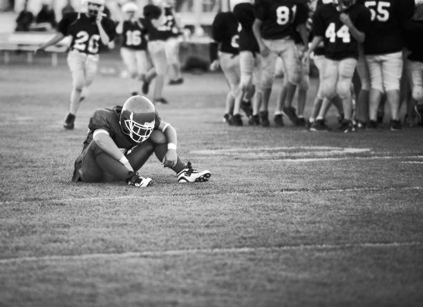 jogador de futebol americano americano sentado no campo - defeat imagens e fotografias de stock