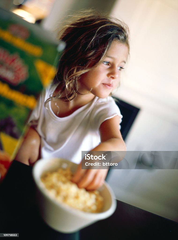 Bambina seduta in cucina e mangiare cereali in ciotola - Foto stock royalty-free di Arredamento