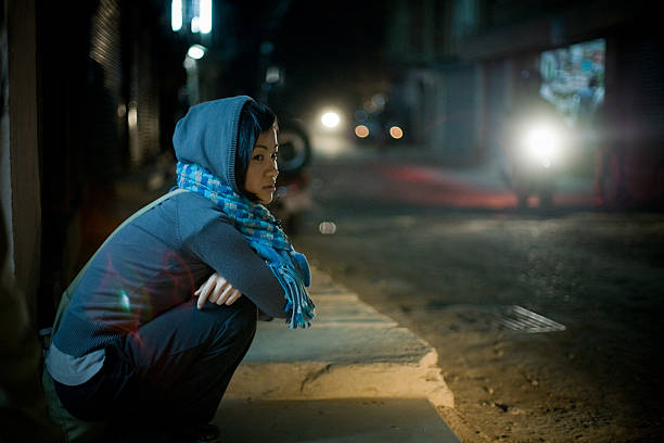 Asian woman sitting on street at night stock photo