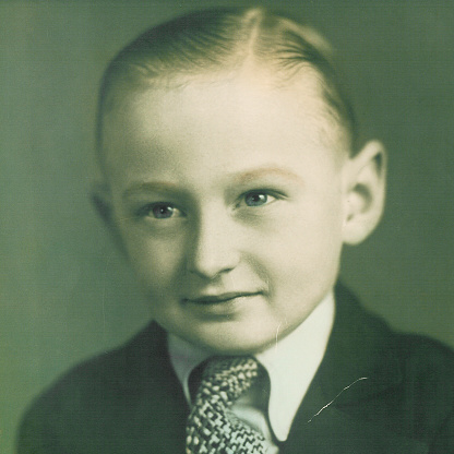 Headshot of a smiling pensive little boy looking at the camera