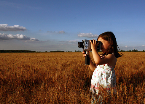 Little Girl Standing in Field and Filming with Vintage Camera