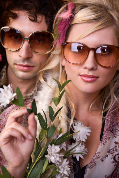 若い hippie の花を持つ男性と女性 - 1970s style hippie couple retro revival ストックフォトと画像