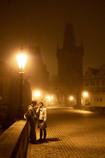 Couple Standing on Bridge in Prague at Night stock photo