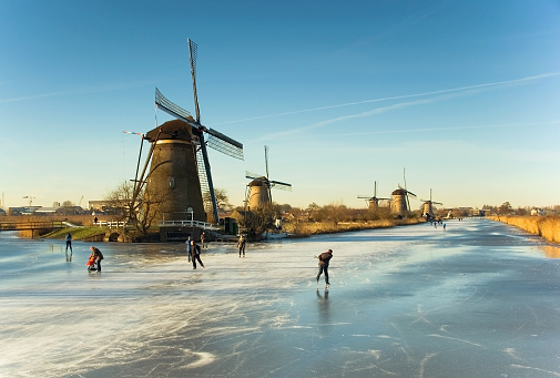 Ice skating on the Braassemermeer near Roelofarendsveen in the municipality of Kaag en Braassem mede Veendermolen on a sunny day. It is mid-February 2021 in the Netherlands, people are skating on a large lake.