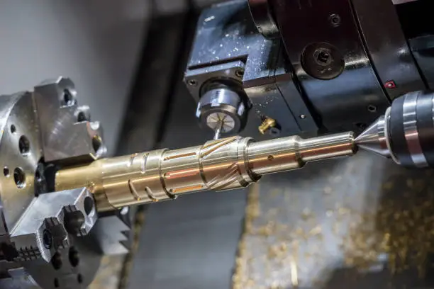 The CNC lathe machine cutting  the slot groove at the brass shaft .Hi-technology automotive part manufacturing process.