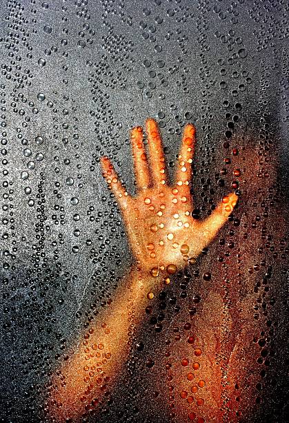 Raindrops on a wet car window with a blurred background. View from inside the vehicle on a gloomy day, creating a moody and atmospheric abstract texture with copy space.