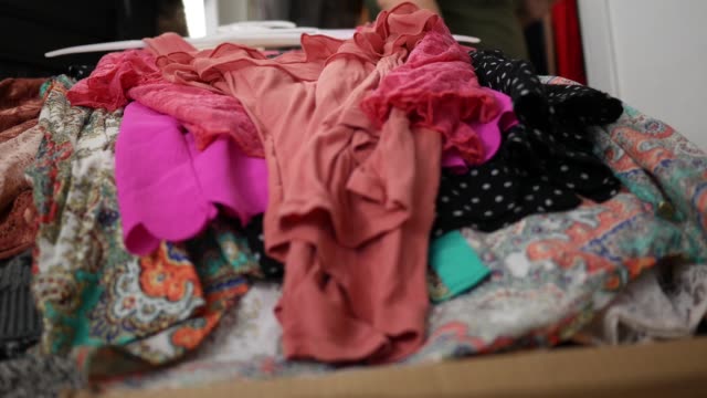Close up of clothing piling up on bedroom bed - hoarding concept