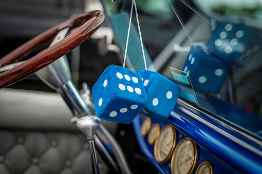 Blue fuzzy dice hanging from vintage car rearview mirror