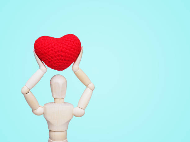 istock wood man figure holding heart shape cushion 1097198196