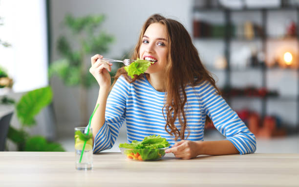 gesunde ernährung. fröhliches junges mädchen essen salat morgen in küche - rohkosternährung stock-fotos und bilder