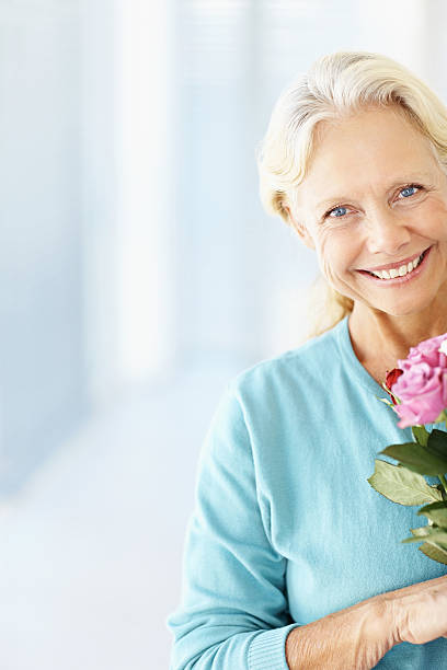 istock Happy mature lady holding a fresh flower with copy space 109720361