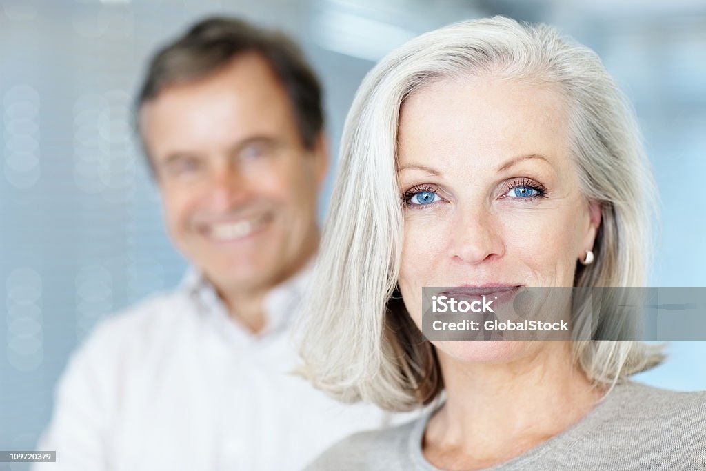 Reife Frau lächelt mit Mann im Hintergrund - Lizenzfrei Frauen Stock-Foto