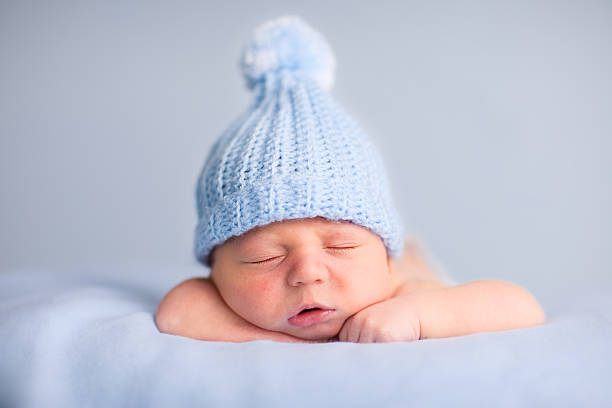 newborn baby boy de dormir tranquilamente usando sombrero de tejido - bebé fotos fotografías e imágenes de stock