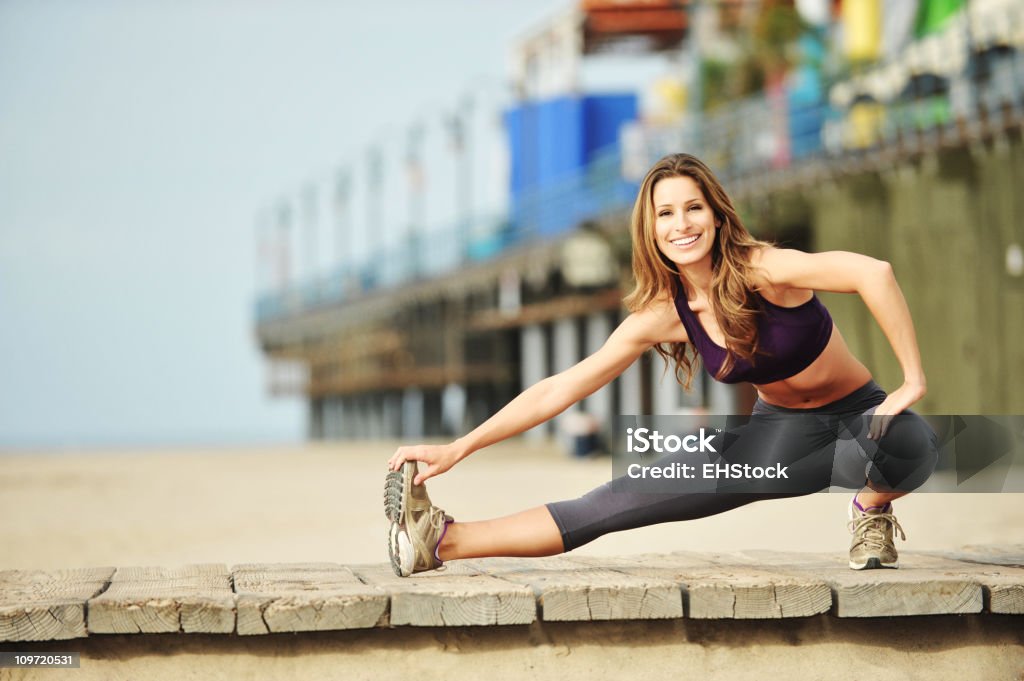 Giovane donna Jogger Stretching sulla spiaggia vicino al molo di Santa Monica - Foto stock royalty-free di Adulto