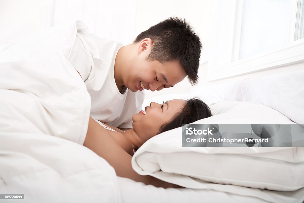 Giovane Coppia felice asiatico sdraiati a letto - Foto stock royalty-free di 20-24 anni