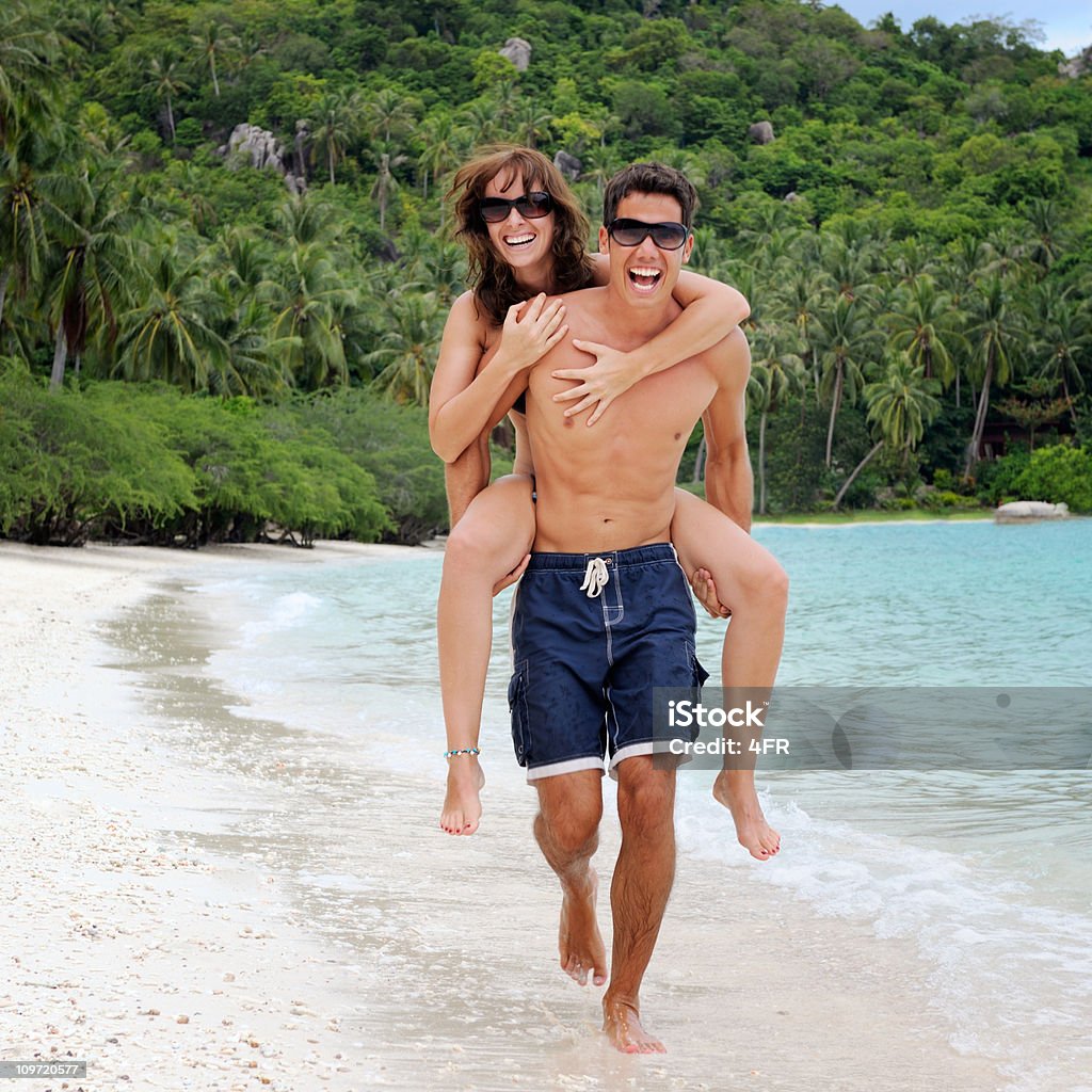 Coppia in esecuzione in un paradiso di palme sulla spiaggia Riva (XXXL - Foto stock royalty-free di 20-24 anni