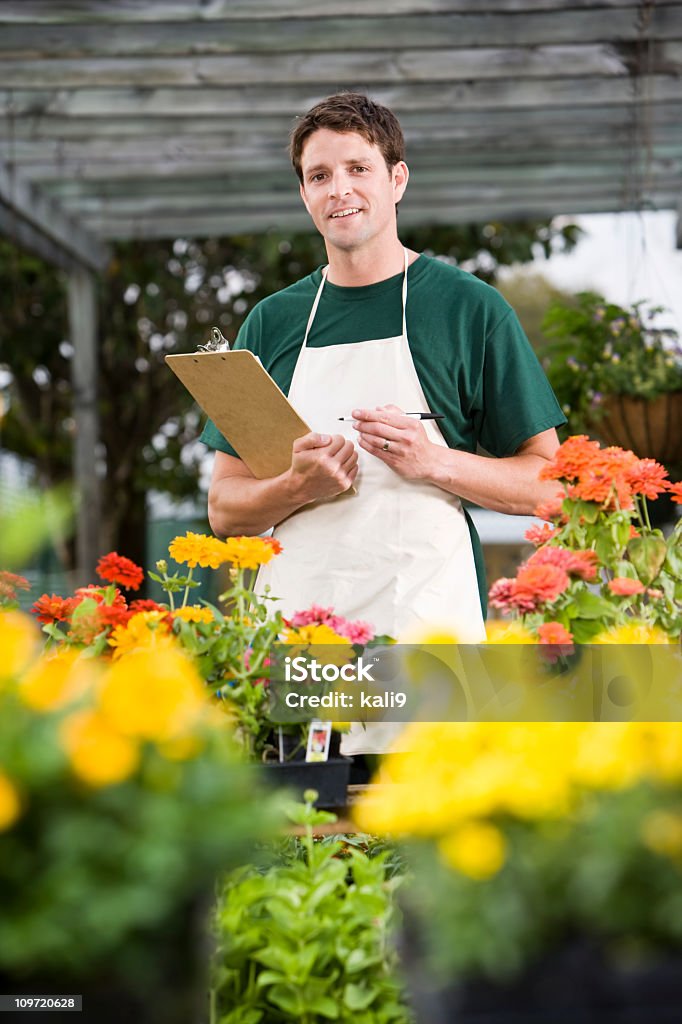 Worker taking inventory in retail garden center Male worker taking inventory in retail garden center surrounded by flowers 30-34 Years Stock Photo