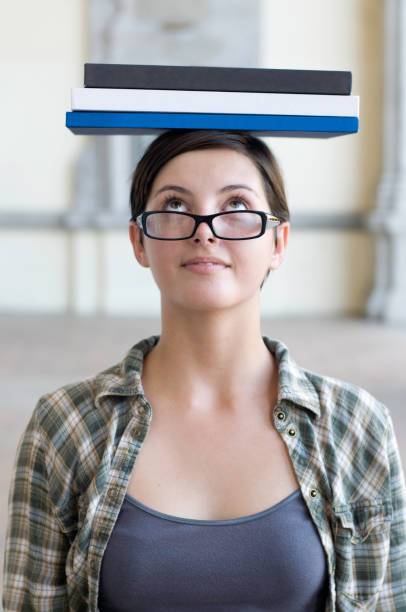 たいテキストブックで彼女の頭でバランスを整えます。 - balance book university glasses ストックフォトと画像