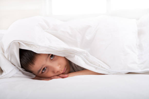 istock Sad little boy laying under blanket 109720810