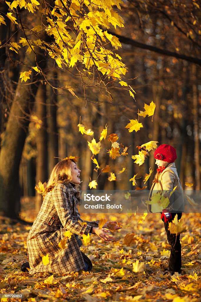 Madre e hija tirar seca las hojas en otoño parque - Foto de stock de Niñas libre de derechos
