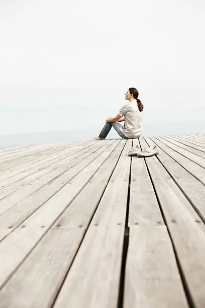 Photo of Woman day dreaming while sitting on a pier