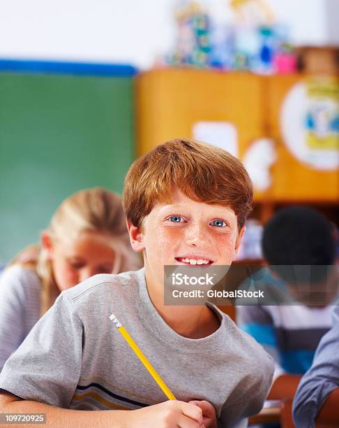 Photo libre de droit de Écolier Garçon Écrit Des Notes Dans Une Salle De Classe banque d'images et plus d'images libres de droit de Salle de classe