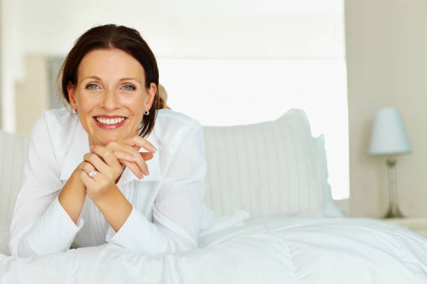 istock Smiling mature lady leans chin on her hands whilst on bed 109720995