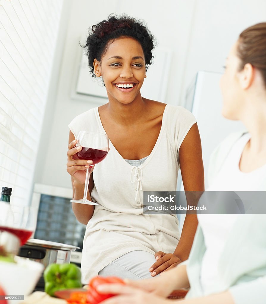 Sonriente joven amigos teniendo una charla mientras la preparación de alimentos - Foto de stock de 20-24 años libre de derechos