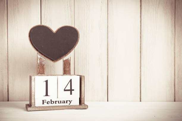 Valentines Day card with wooden block calendar on white wooden background witn copy space for text. stock photo
