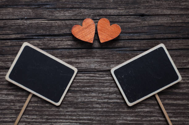 Valentines day concept. Two red hearts and two black plank for text on old wooden background. stock photo
