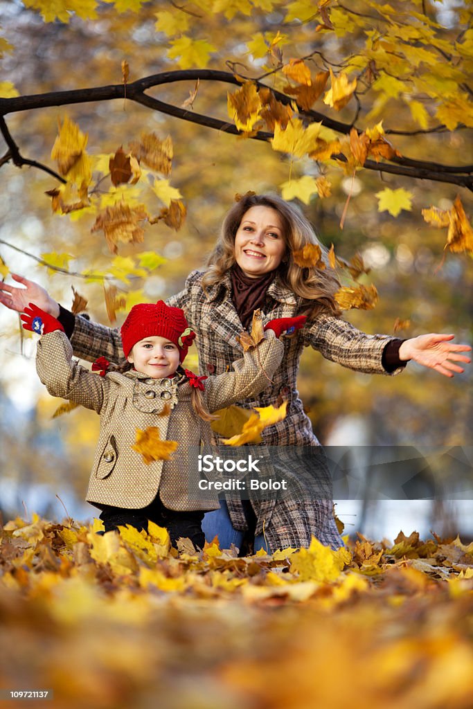 Мать и дочь Бросать сухие листья в Осенний Парк - Стоковые фото 6-7 лет роялти-фри
