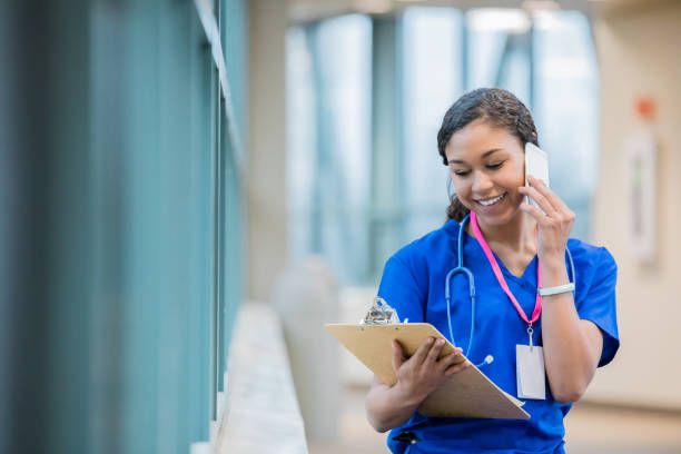 젊은 간호사 또는 의료 전문가 병원에서 환자의 차트를 읽는 동안 전화 통화 하 게 - student printed media walking clothing 뉴스 사진 이미지