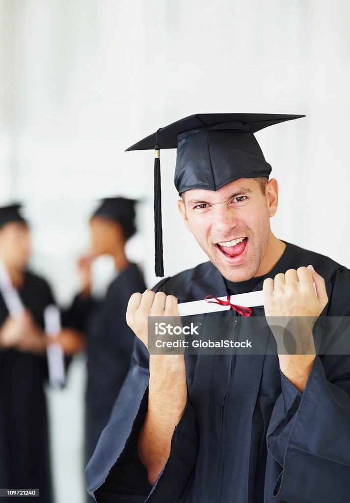 Excitación hombre que agarra graduación certificado con amigos en el fondo - Foto de stock de 20-24 años libre de derechos