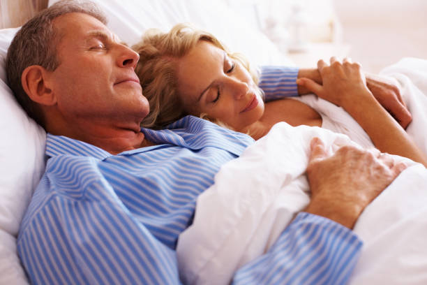 mature couple sleeping together in bed - ogen dicht closeup vrouw 50 jaar stockfoto's en -beelden