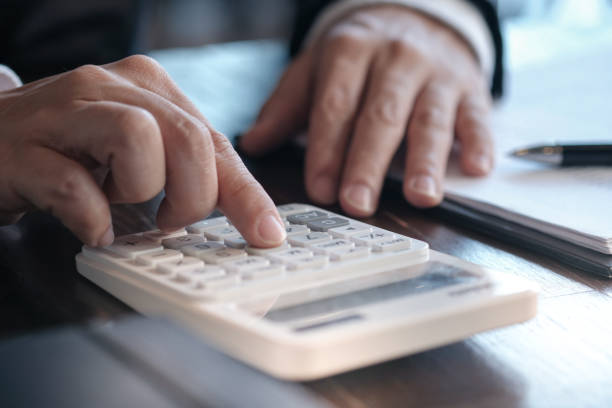 istock Businessman analyzing investment charts and pressing calculator buttons over documents. Accounting Concept. 1097219984