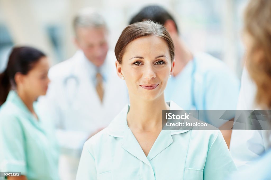 Happy young nurse with her blur medical team in background  20-29 Years Stock Photo