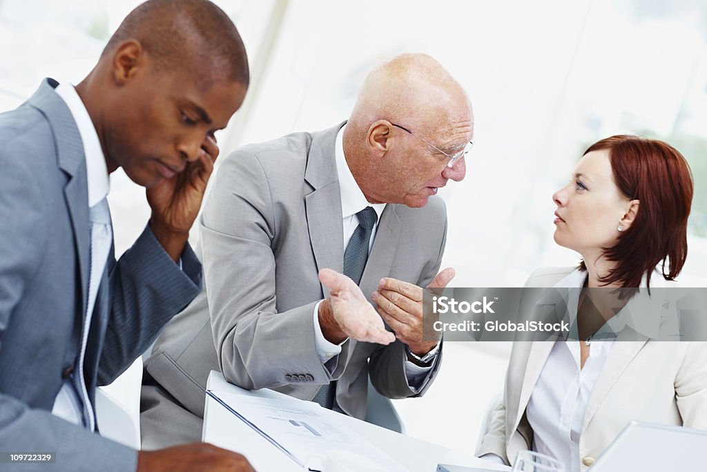 Senior Uomo d'affari con il suo team discutendo in ufficio - Foto stock royalty-free di Abbigliamento da lavoro